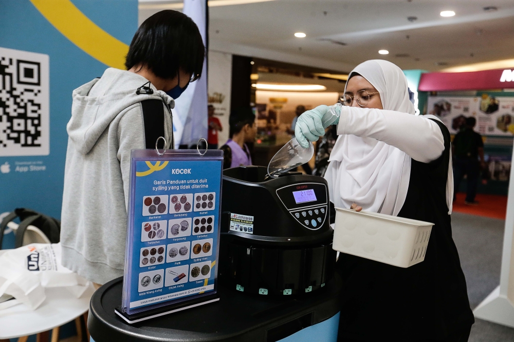 Staff of Kocek attend to a customer as they sort the coins during My Digital Maker event at Quill City Mall, Kuala Lumpur, October 8, 2023. — Picture by Sayuti Zainudin
