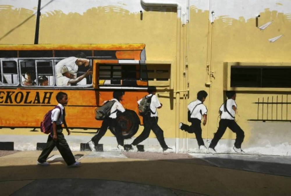 A school boy walks past a street mural depicting a school bus and students in Shah Alam, January 2, 2014. — eNM pic