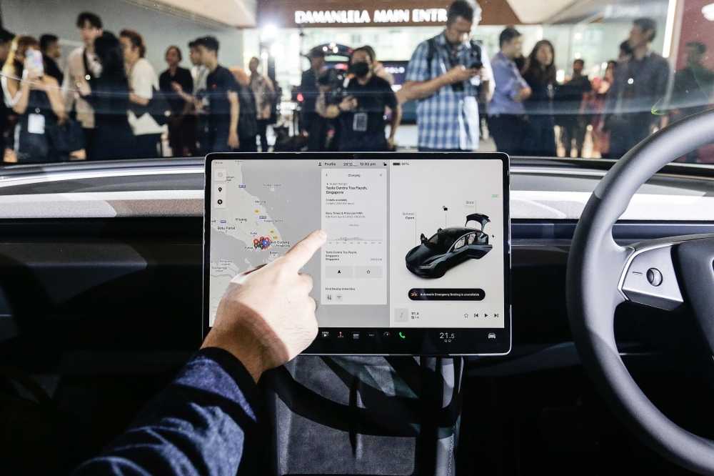 Visitors try out the touchscreen display screen in the new Model 3. — Picture by Sayuti Zainudin