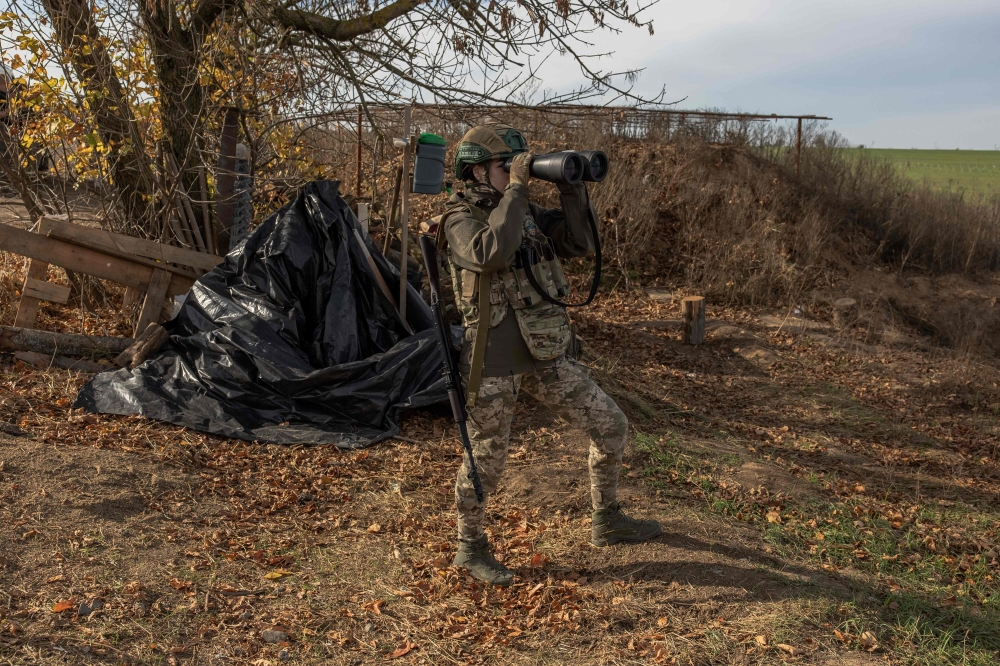 A Ukrainian military member checks the area with binoculars at a position outside the southern city of Kherson, on November 2, 2023, amid Russia’s military invasion on Ukraine. Ukraine’s most senior military official said that the nearly two-year conflict with Russia had reached a stalemate, with Russia rejecting the comments. — eNM pic