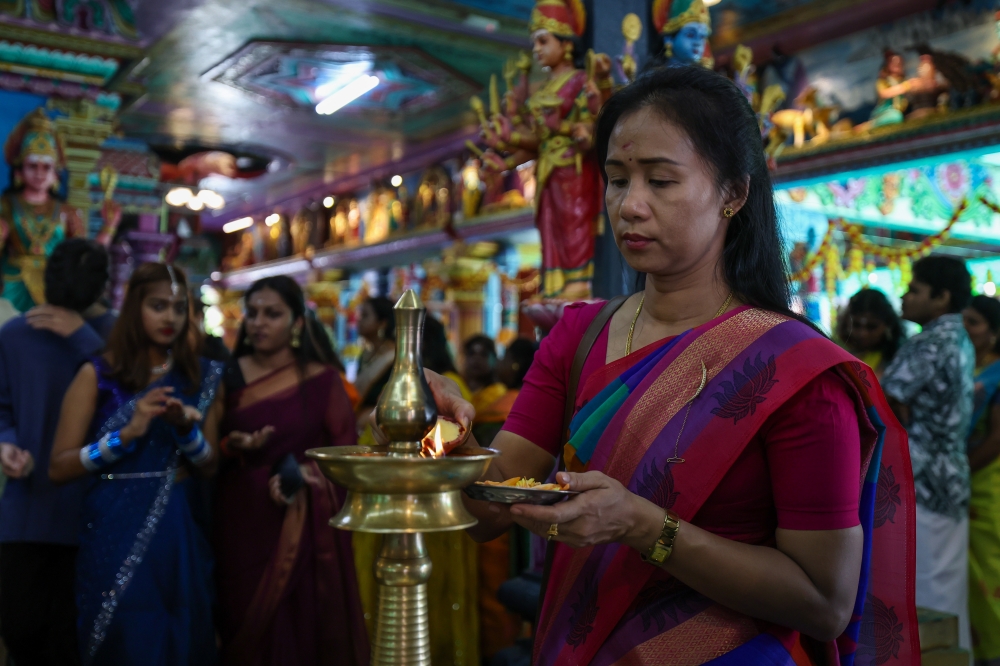 A devotee lights a vilakku or tradition lamp while performing prayers in conjunction with Deepavali at the Arulmigu Karumariamman temple in Butterworth. — eNM pic