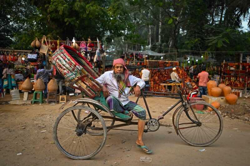 This photograph taken on December 14, 2023 shows bicycle rickshaw driver Mohammad Chan Mia posing for a portrait with his vehicle in Dhaka. — eNM pic