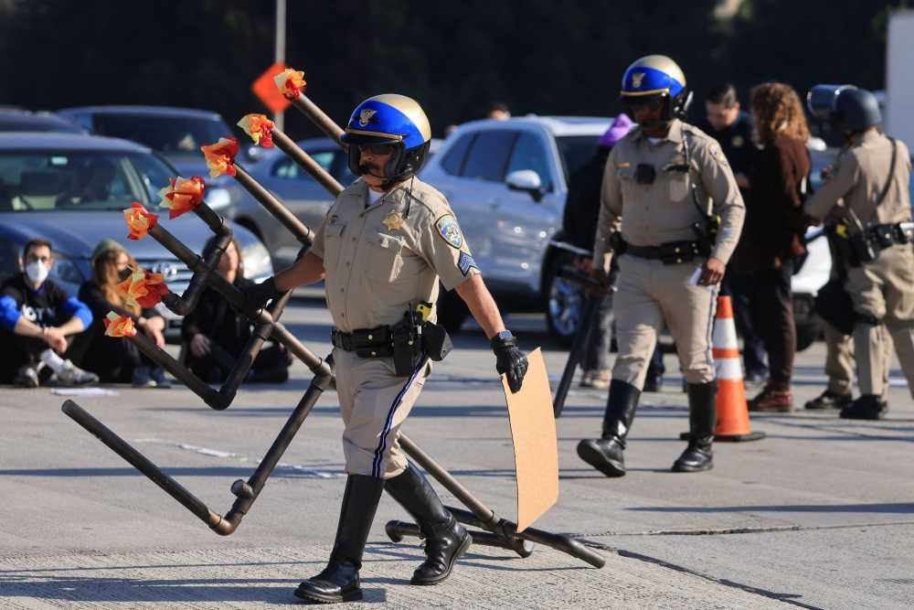A law enforcement officer removes a Hanukkiyah, a candlestick with nine branches that is lit to mark Hanukkah, placed by demonstrators demanding a ceasefire and an end to US support for Israel's attack on Gaza to block morning traffic on the 110 Freeway, in Los Angeles December 13, 2023. — eNM pic