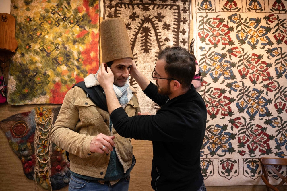 Yunus Girgic adjusts as he delivers a symbolic hat 'Sikke', worn by whirling dervishes, to his customer Ashmi Benmehidi. — eNM pic