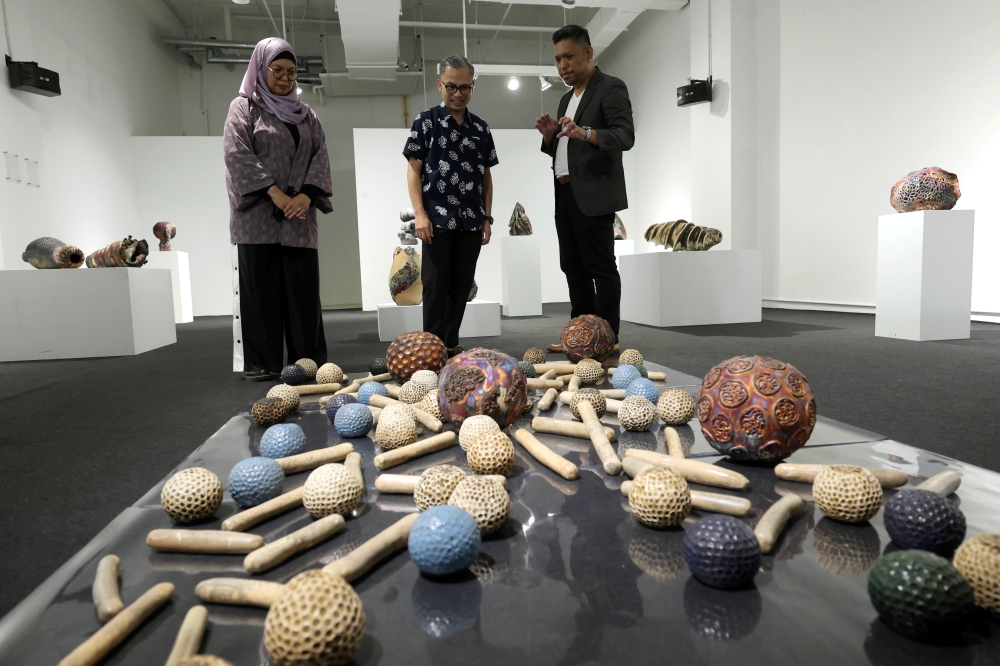 Communications Minister Fahmi Fadzil (centre) listens as ceramic artist Adil Abdul Ghani (right) explains his artwork during the ‘Life: Magnified — The Main Show’ exhibition at Zhan Art in Kuala Lumpur January 13, 2024. — eNM pic