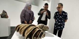 Communications Minister Fahmi Fadzil (right) listens as ceramic artist Adil Abdul Ghani (centre) explains his artwork during the ‘Life: Magnified — The Main Show’ exhibition at Zhan Art in Kuala Lumpur January 13, 2024. — eNM pic