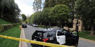Police cars are seen behind caution tape outside the home of US producer and musician Sean 