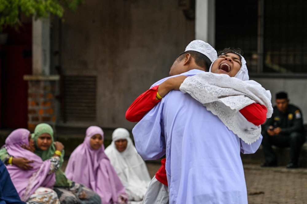 Rohingya refugees embrace each other after taking part in Eid al-Fitr prayers, marking the end of the holy month of Ramadan, at a temporary shelter in Meulaboh, Indonesia's Aceh province April 10, 2024. — eNM pic