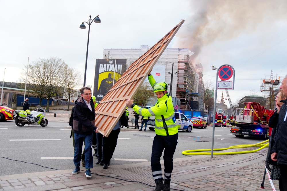 Former Danish Minister of Culture and current CEO of Danish Business (Dansk Erhverv), Brian Mikkelsen, assists with the evacuation of paintings after a fire broke out at the Old Stock Exchange, Boersen, in Copenhagen, Denmark April 16, 2024. — Ritzau Scanpix/Ida Marie Odgaard pic via eNM 