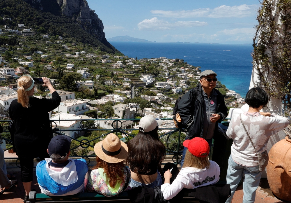 People sit on a bench and take photos on Capri Island, Italy, April 18, 2024. — eNM pic  