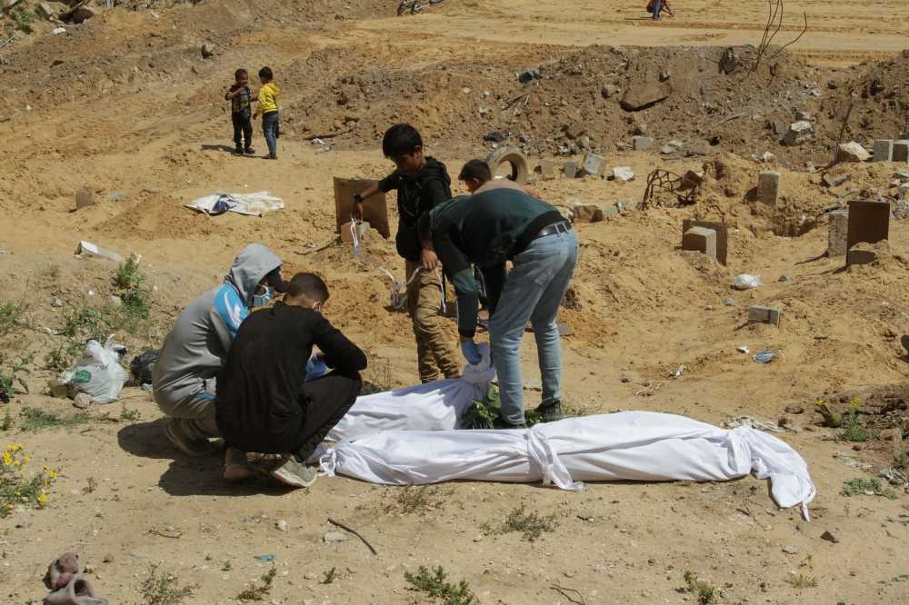 Palestinians cover a body, which was buried in a mass grave, amid the ongoing conflict between Israel and Hamas, in northern Gaza Strip, April 15, 2024. ― eNM pic