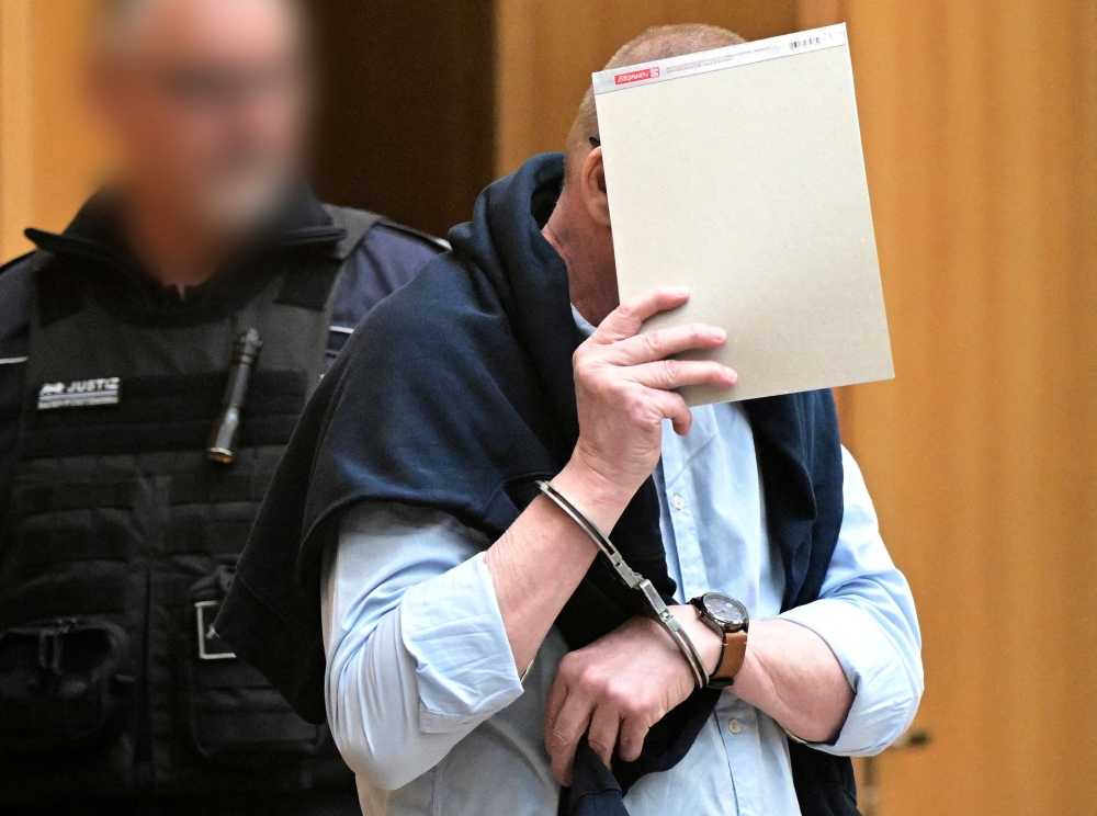 A defendant in handcuffs arrives in a courtroom were nine men go on trial charged with high treason, attempted murder and plotting a violent coup d'etat aimed at installing an aristocrat as national leader and imposing martial law, in Stuttgart April 29, 2024. — Bernd Weißbrod/Pool/eNM pic