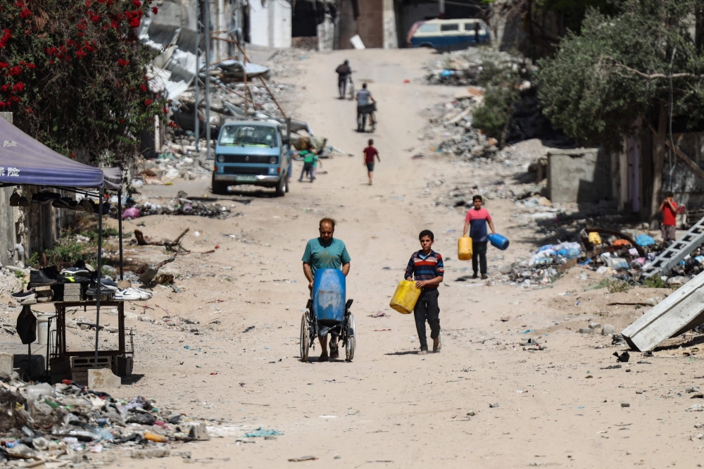 Palestinians carry recipients as they walk toward a water distribution point along a street devastated by Israeli bombardment in Gaza City on May 3, 2024, amid the ongoing conflict between Israel and the militant group Hamas. ― eNM pic