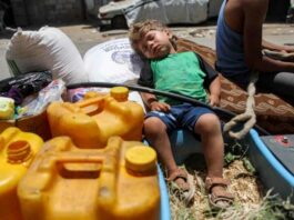 A boy sleeps on a sack of flour next to jerrycans in the back of an animal-drawn cart while evacuating from the Tuffah neighbourhood in the east of Gaza City heading towards areas in the west June 24, 2024 amid the ongoing conflict in the Palestinian territory between Israel and Hamas. — eNM pic