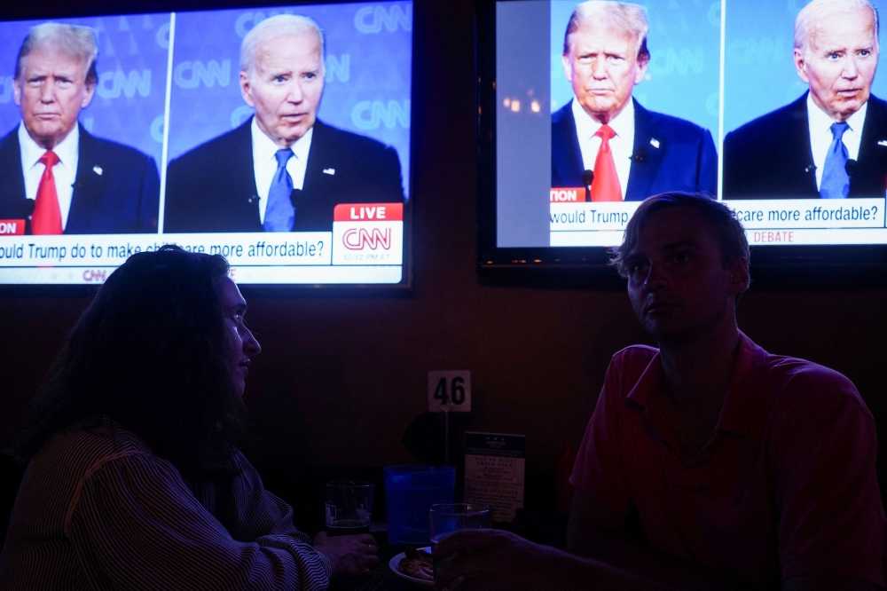 Republican presidential candidate, former US President Donald Trump and Democrat presidential candidate, US President Joe Biden are seen on television as people attend a watch party for the first US presidential debate hosted by CNN in Atlanta, at Union Pub on Capitol Hill in Washington June 27, 2024. — eNM pic